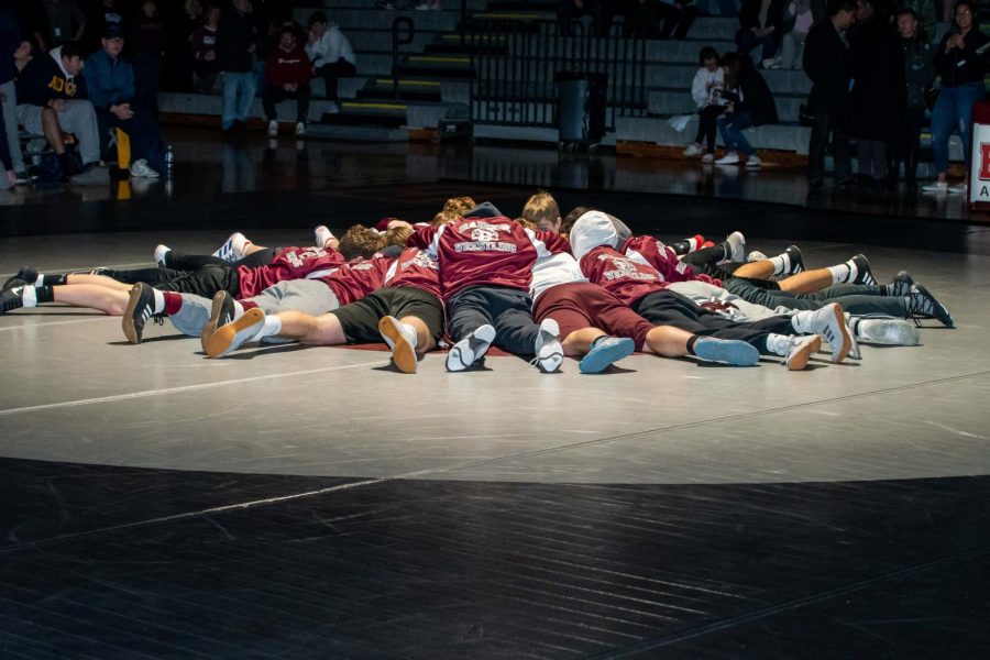 FIGHTING FOR OUR HOME! The wrestling team gathers in the middle of the mat before their harsh match in order to win at home.