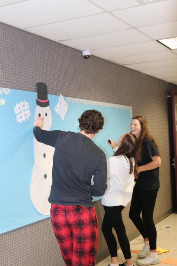 WHATS SNOW FUNNY? Juniors Blake Kornafel, Aubreana Collura, and Grace Plimpton crack jokes as they construct the snowman. Each year students create a different winter theme for the hallway.